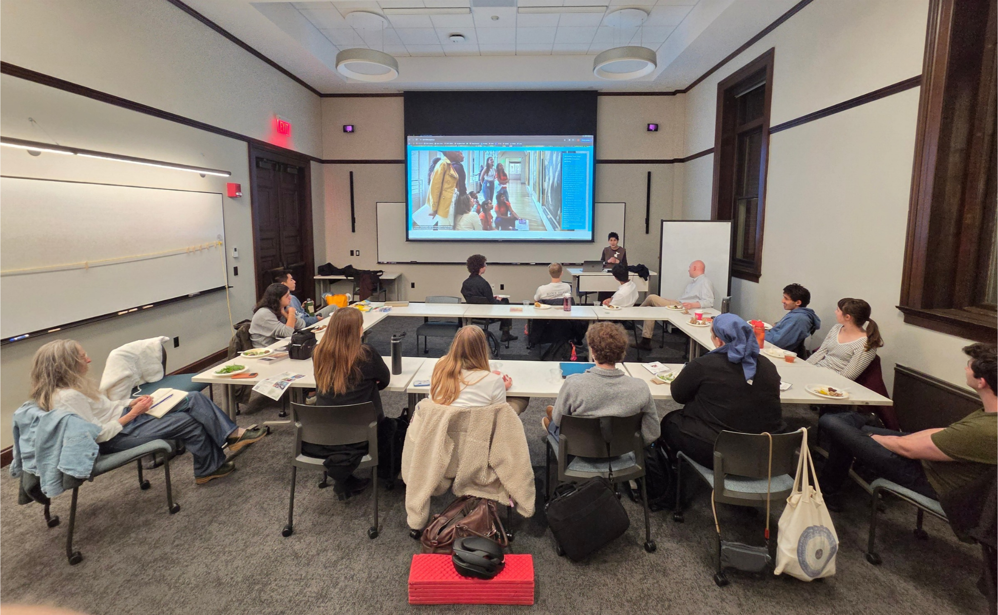 Students around a table looking at a screen with images of students on it