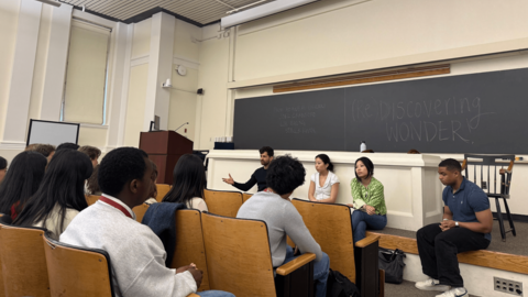 A panel of sits in front of a classroom audience.