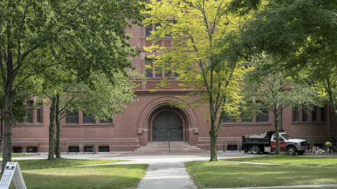 A picture of a class building hidden behind trees.
