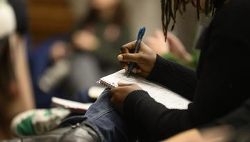 Up close photo of student writing on a notepad.