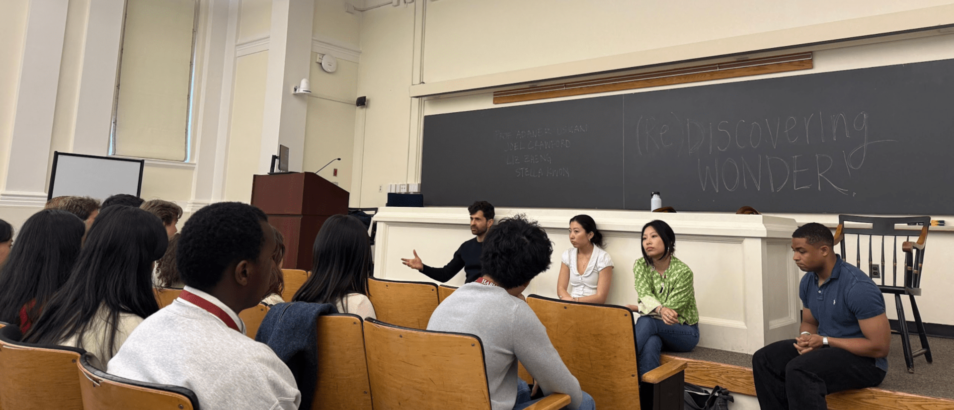 A panel of sits in front of a classroom audience.