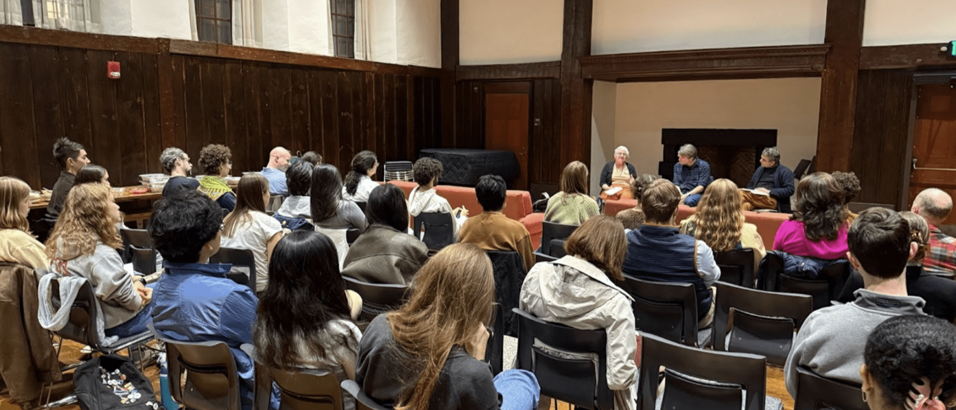 People seated in a room listening to a panel discussion at the front.