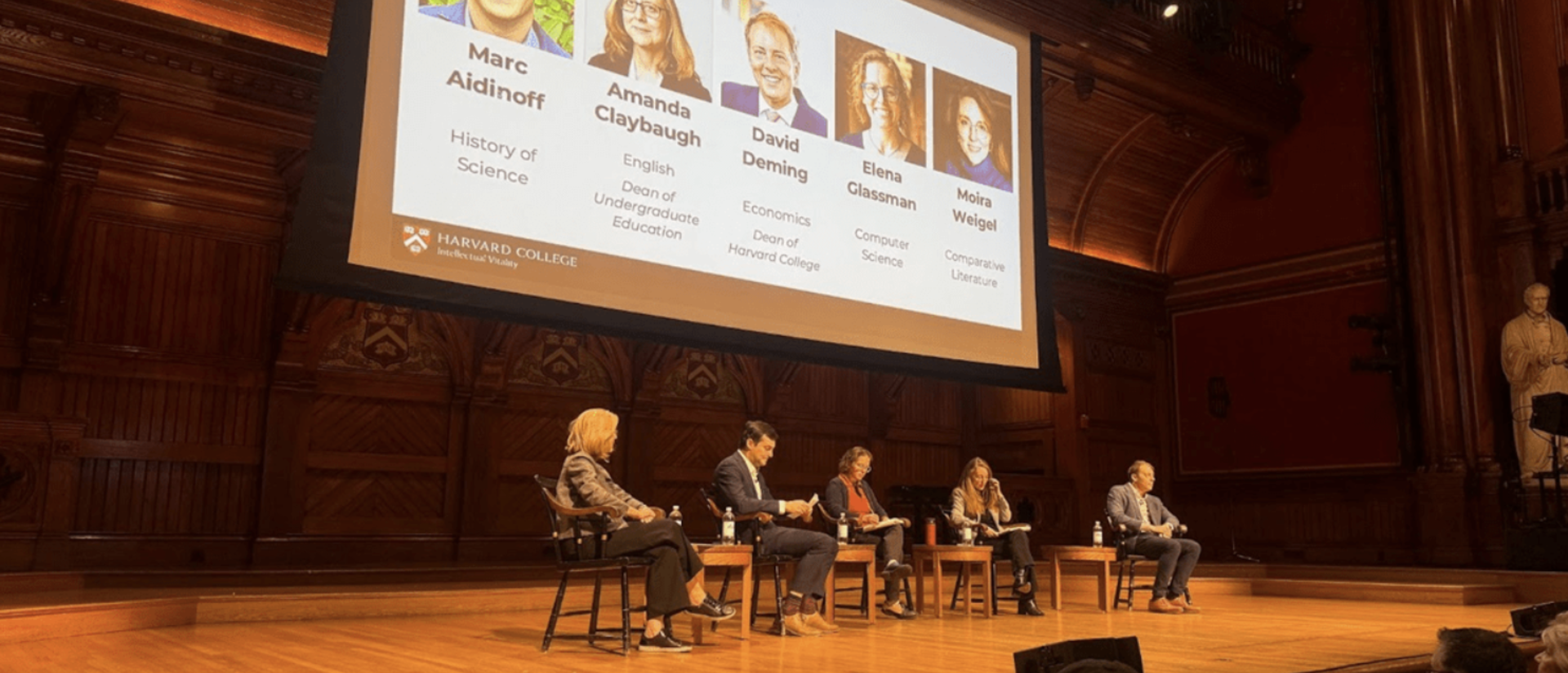 Five panelists having a discussion in front of a large audience
