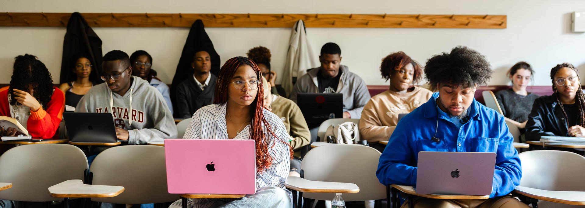 Students seated in a classroom with laptops out and have their attention to the front.