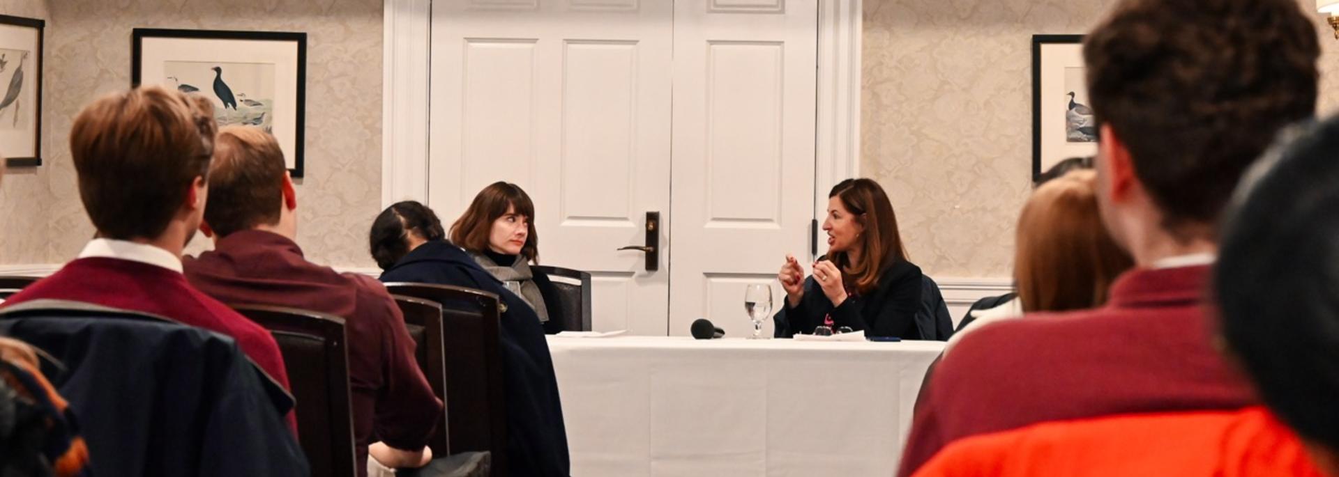 Two faculty discuss in front of a room full of students.