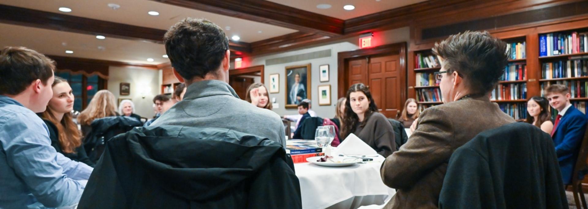 Students and faculty sit for dinner and converse. 